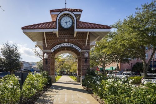 Scenic view of Winter Garden, Florida, featuring charming historic buildings lining a vibrant downtown street, with colorful storefronts and lush greenery under a clear blue sky.